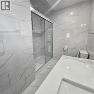 Bathroom with walk in shower, toilet, and tile walls -