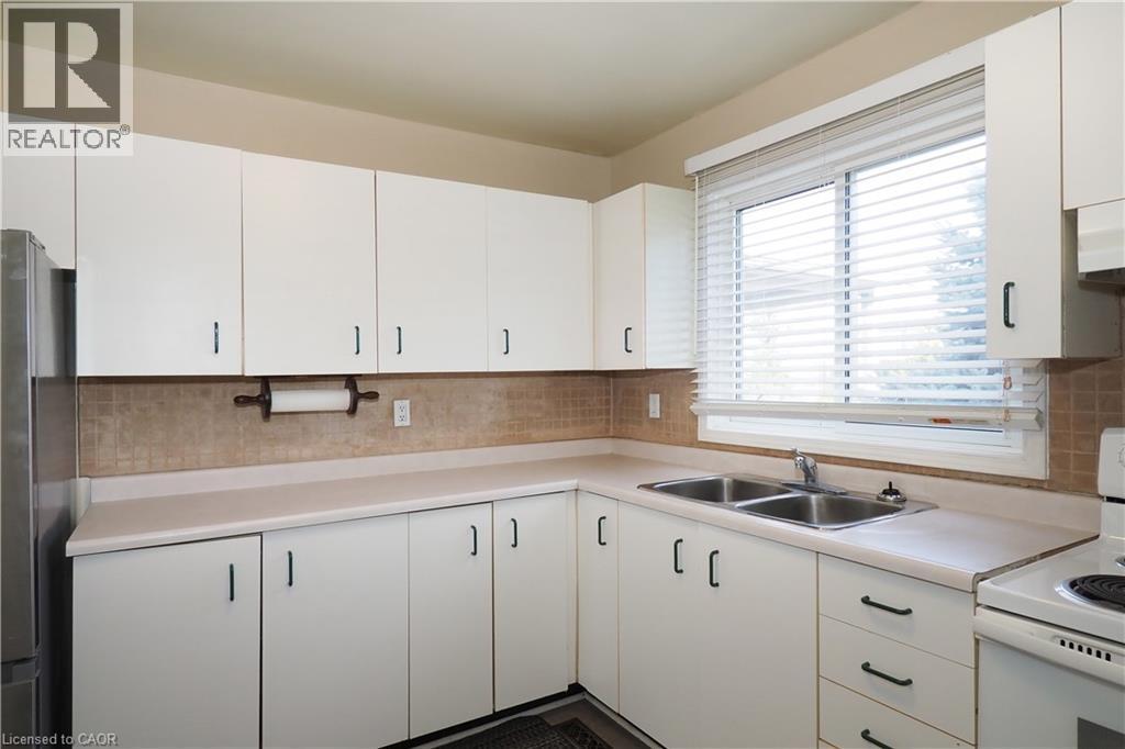Kitchen featuring white range with electric stovetop, light countertops, and white cabinetry - 255 Northlake Drive Unit# 27, Waterloo, ON - Indoor Photo Showing Kitchen With Double Sink
