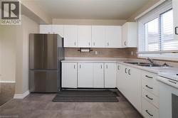Kitchen with freestanding refrigerator, light countertops, backsplash, and white cabinetry -