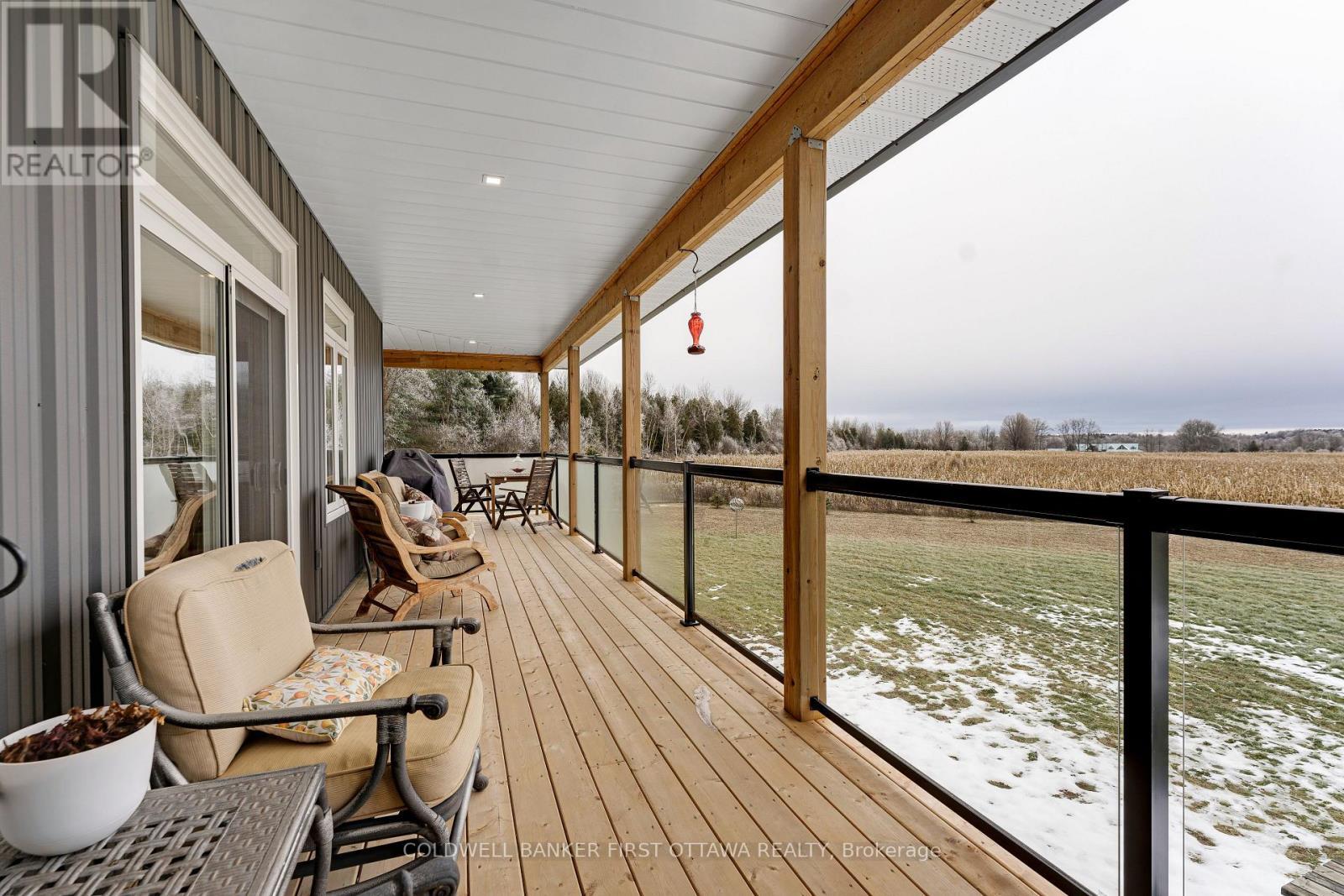 Wrap-about deck with metal frame & glass railing - 462 Althorpe Road, Tay Valley, ON - Outdoor With Exterior