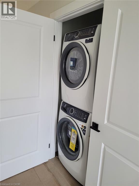 Laundry room featuring estacked washer and dryer and wood finished floors - 269 Dumfries Avenue Unit# Main, Kitchener, ON - Indoor Photo Showing Laundry Room