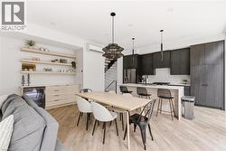 Dining area featuring stairs, beverage cooler, light wood finished floors, and a wall unit AC -