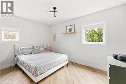 Bedroom featuring light wood-type flooring and multiple windows -