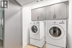 Laundry room with cabinet space, washer and dryer, and light wood-style floors -