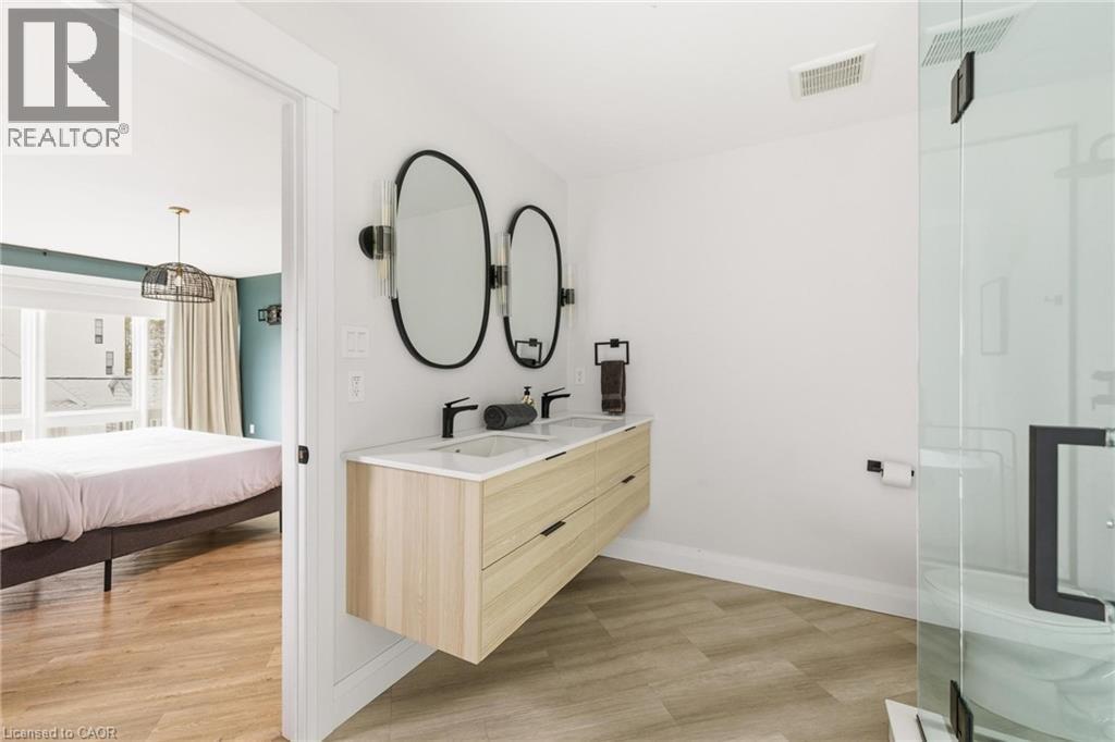 Bathroom with double vanity, a stall shower, and light wood-style floors - 26 Huron Street, Grand Bend, ON - Indoor