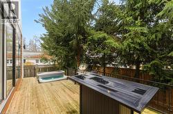 Wooden deck with a fenced backyard and a grill -