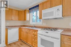 Kitchen featuring white appliances, light countertops, light wood-style floors, and light brown cabinetry -