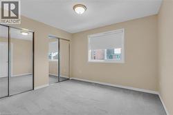 Unfurnished bedroom with two closets, carpet, and multiple windows -
