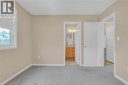 Unfurnished bedroom featuring light carpet and ensuite bath -