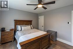 Bedroom with ceiling fan and dark wood-style floors -