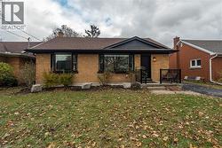 View of front facade with a front yard, brick siding, covered porch, a chimney, and roof with shingles -