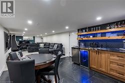 Indoor wet bar featuring open shelves, brown cabinets, wine cooler, recessed lighting, and dark stone counters -