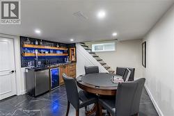 Indoor wet bar featuring dark countertops, open shelves, dark marble finish flooring, wine cooler, and stairs -