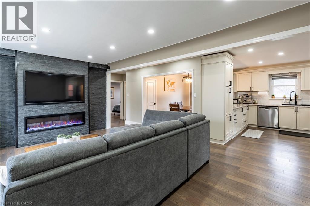Living area with dark wood finished floors, recessed lighting, and a stone fireplace - 266 Melrose Avenue, Kitchener, ON - Indoor Photo Showing Living Room With Fireplace