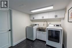 Laundry room with dark marble finish floors, cabinet space, and washing machine and clothes dryer -