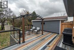 Wooden terrace with a storage unit, area for grilling, and a pergola -