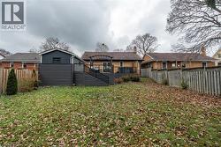 Rear view of house with a fenced backyard, a deck, stairs, and brick siding -