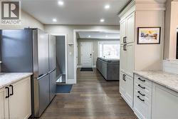 Kitchen featuring freestanding refrigerator, light stone counters, dark wood finished floors, open floor plan, and recessed lighting -