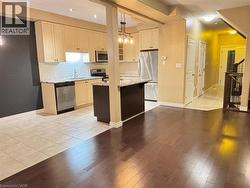 Kitchen with light stone counters, stainless steel appliances, light wood-style floors, a center island, and pendant lighting -