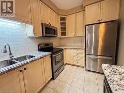 Kitchen with stainless steel appliances, light stone countertops, glass insert cabinets, and backsplash -