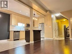 Kitchen featuring a kitchen breakfast bar, appliances with stainless steel finishes, light wood-type flooring, decorative light fixtures, and light stone counters -