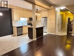Kitchen featuring light stone counters, stainless steel appliances, light wood-style floors, a kitchen island, and pendant lighting -