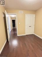 Unfurnished bedroom featuring dark wood-style flooring, a textured ceiling, and a closet -