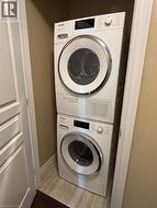 Laundry room with stacked washing machine and dryer and light wood-style floors -