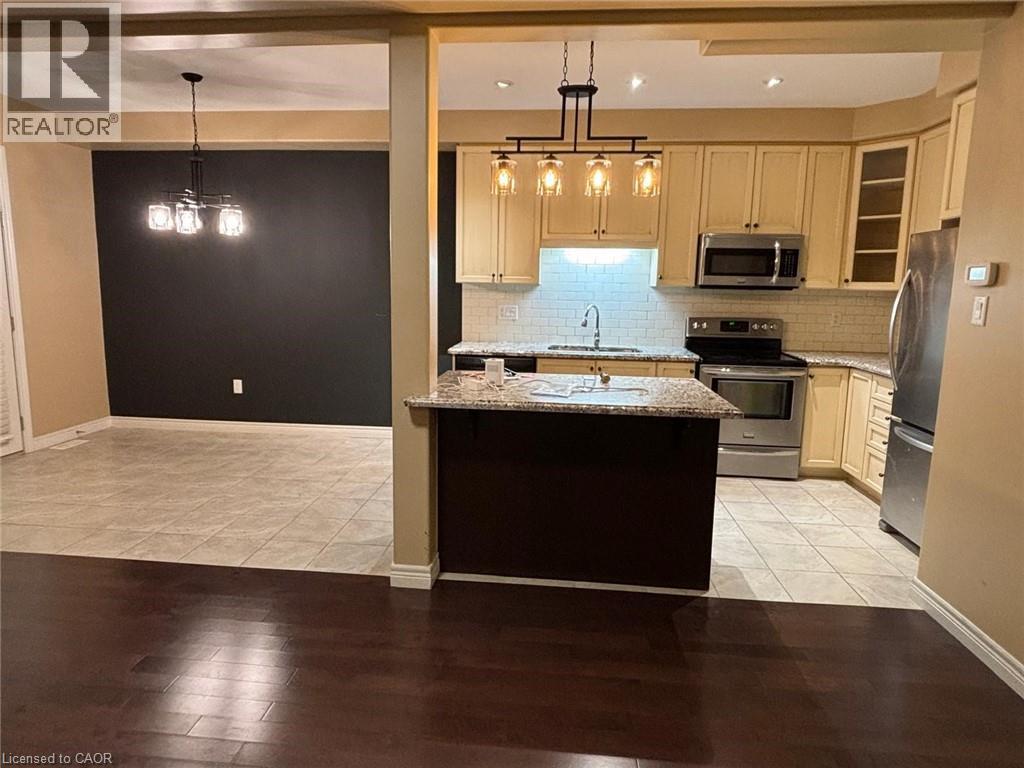 Kitchen with light stone counters, pendant lighting, appliances with stainless steel finishes, light tile patterned floors, and recessed lighting - 6 Chestnut Drive Unit# 16, Grimsby, ON - Indoor Photo Showing Kitchen