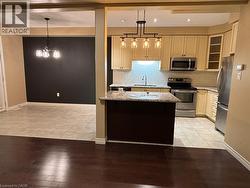 Kitchen with light stone counters, pendant lighting, appliances with stainless steel finishes, light tile patterned floors, and recessed lighting -