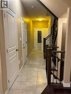 Hallway with stairs and light tile patterned flooring -