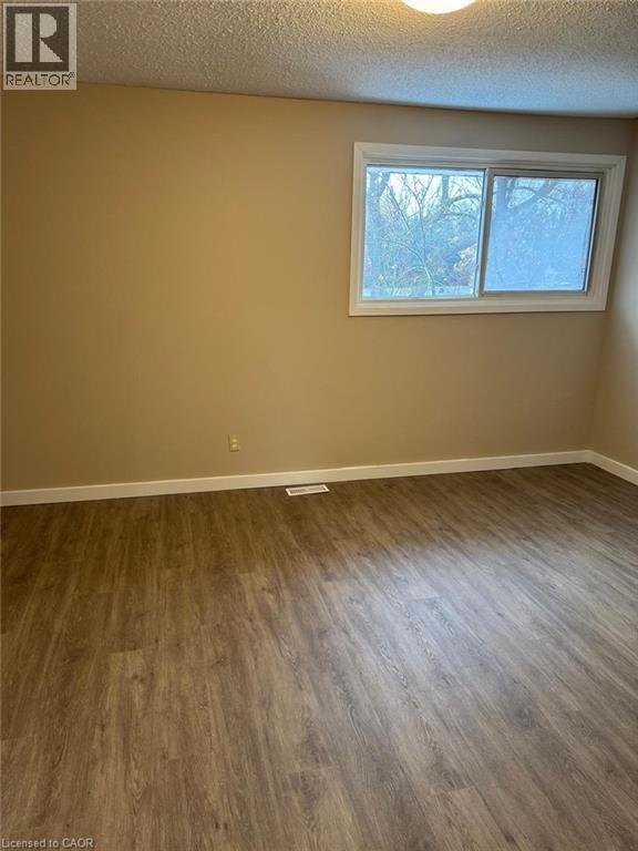 Spare room featuring a textured ceiling and wood finished floors - 316 Dufferin Street, Stratford, ON - Indoor Photo Showing Other Room