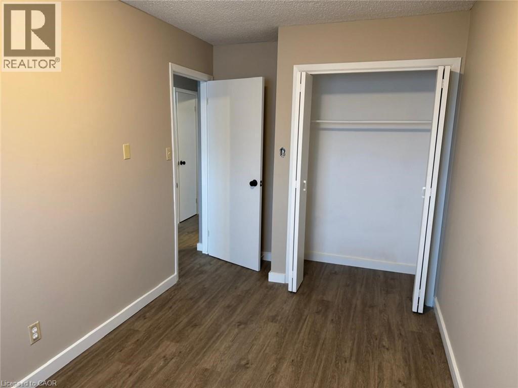 Unfurnished bedroom featuring a textured ceiling, dark wood-style floors, and a closet - 316 Dufferin Street, Stratford, ON - Indoor Photo Showing Other Room