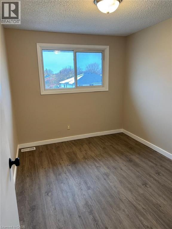 Empty room with a textured ceiling and dark wood-style floors - 316 Dufferin Street, Stratford, ON - Indoor Photo Showing Other Room