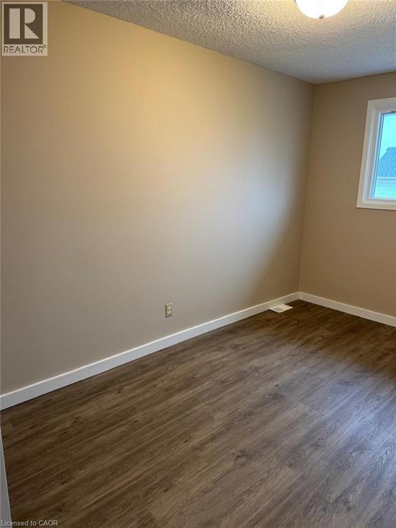 Unfurnished room with dark wood-style floors and a textured ceiling - 316 Dufferin Street, Stratford, ON - Indoor Photo Showing Other Room