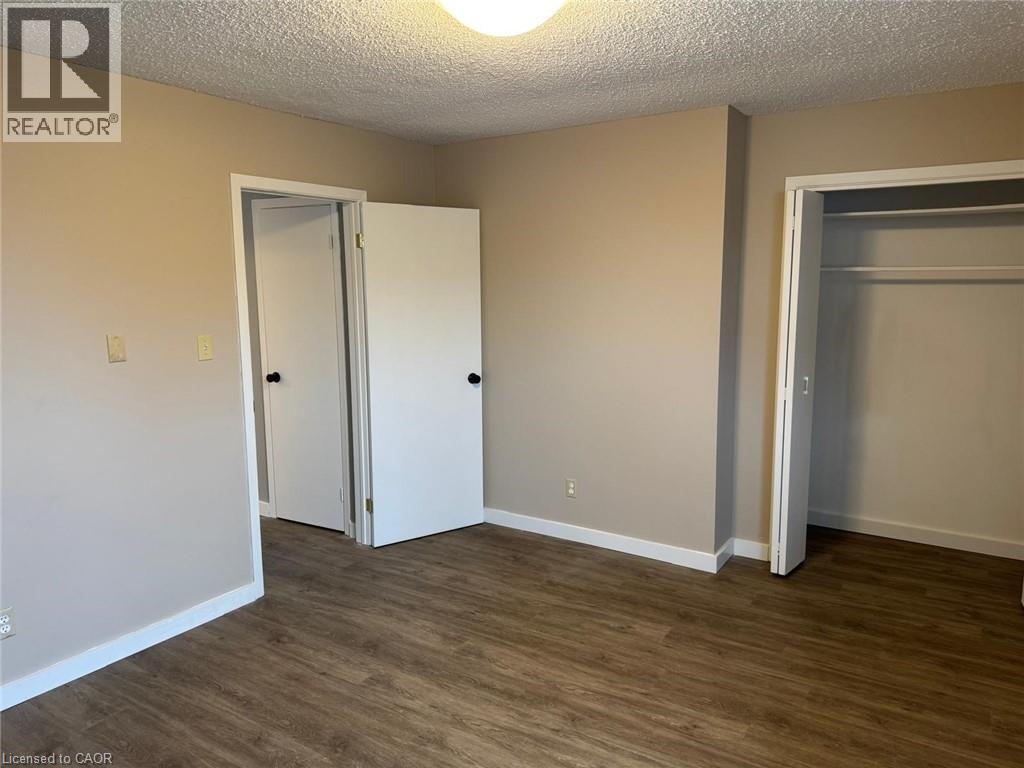 Unfurnished bedroom with a textured ceiling, dark wood-style flooring, and a closet - 316 Dufferin Street, Stratford, ON - Indoor Photo Showing Other Room