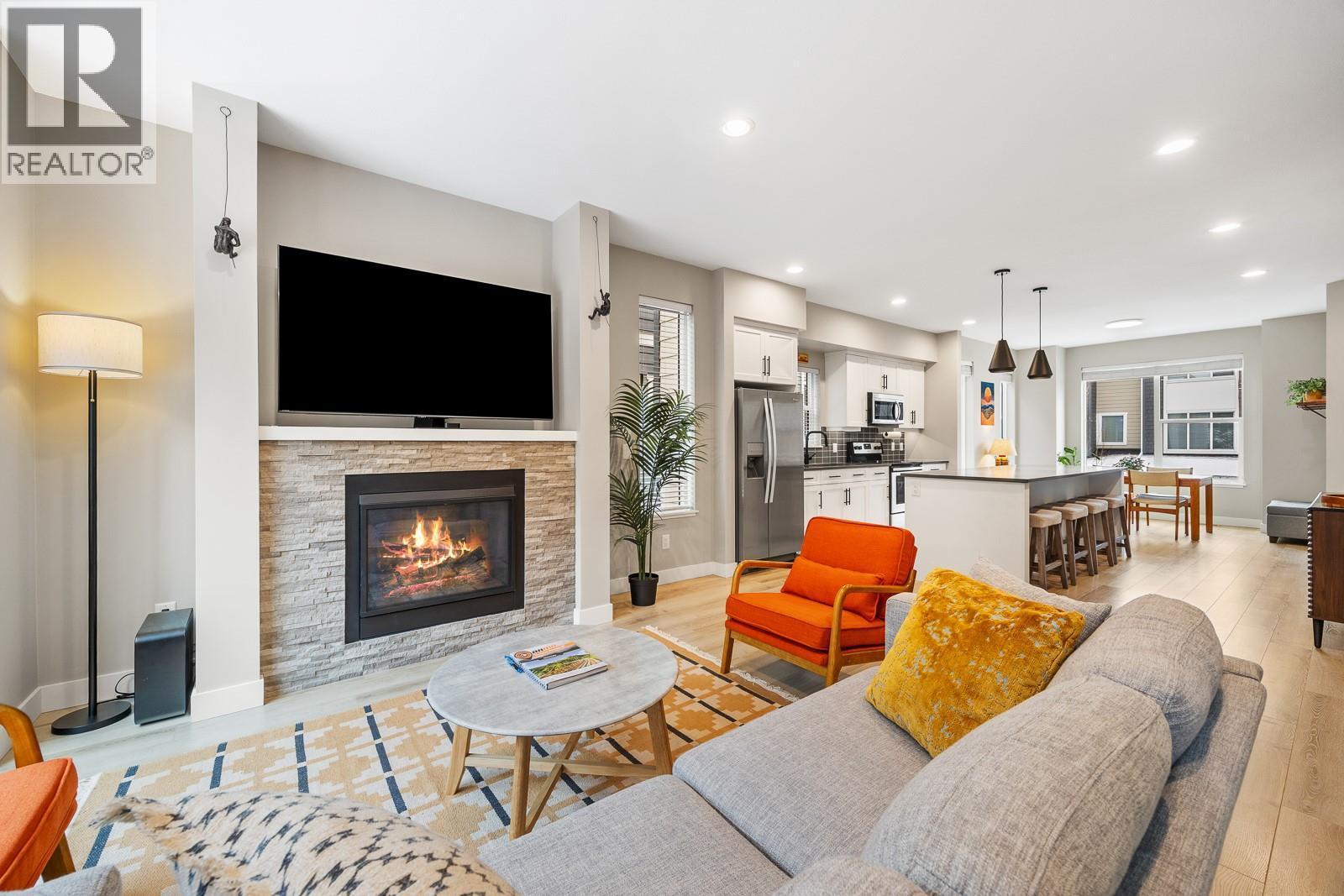 Spacious open-concept living with a cozy fireplace and tons of natural light from the extra end-unit windows. - 2490 Tuscany Drive Unit# 54, West Kelowna, BC - Indoor Photo Showing Living Room With Fireplace