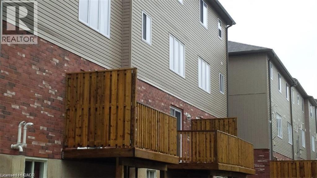 View of home's exterior featuring brick siding and a deck - 55 Mooregate Crescent Unit# 3, Kitchener, ON - With Exterior
