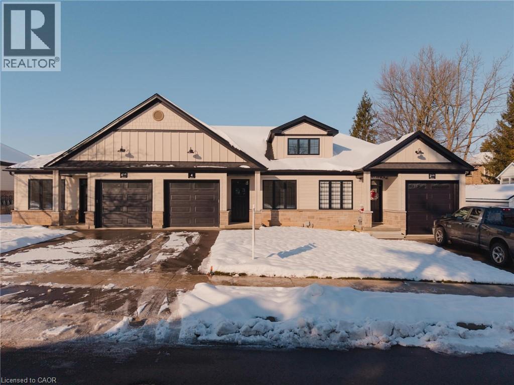 Modern farmhouse style home featuring a garage, stone siding, and driveway - 4 Elgin Street W, Norwich, ON - Outdoor With Facade