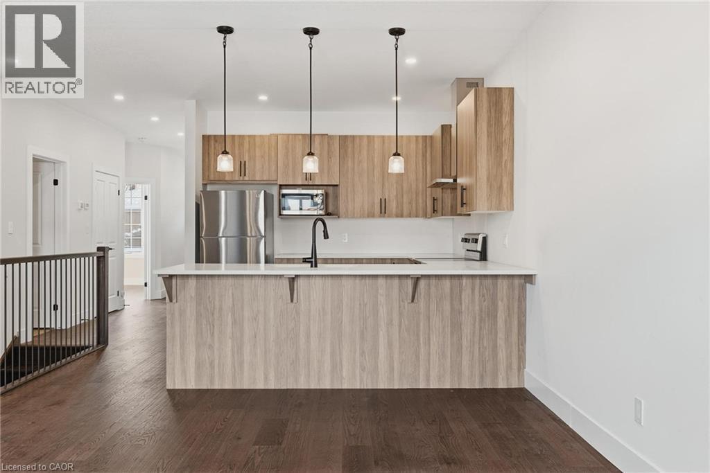 Kitchen with pendant lighting, a peninsula, stainless steel appliances, modern cabinets, and a breakfast bar - 4 Elgin Street W, Norwich, ON - Indoor Photo Showing Kitchen With Upgraded Kitchen