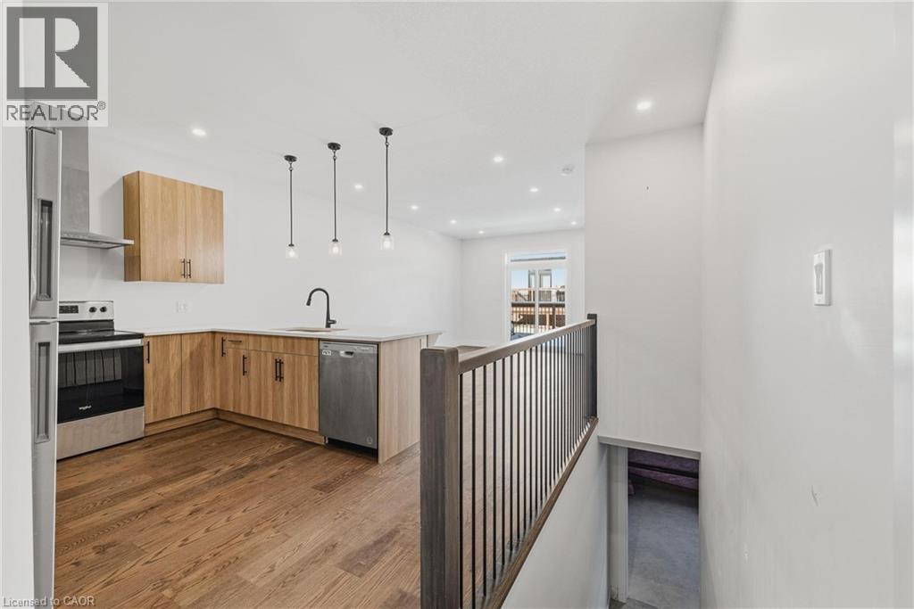 Kitchen featuring stainless steel appliances, hanging light fixtures, a peninsula, recessed lighting, and dark wood finished floors - 4 Elgin Street W, Norwich, ON - Indoor Photo Showing Kitchen