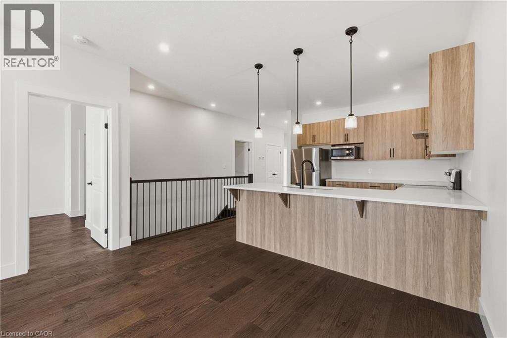 Kitchen with a peninsula, hanging light fixtures, dark wood-style flooring, recessed lighting, and appliances with stainless steel finishes - 4 Elgin Street W, Norwich, ON - Indoor Photo Showing Kitchen With Upgraded Kitchen