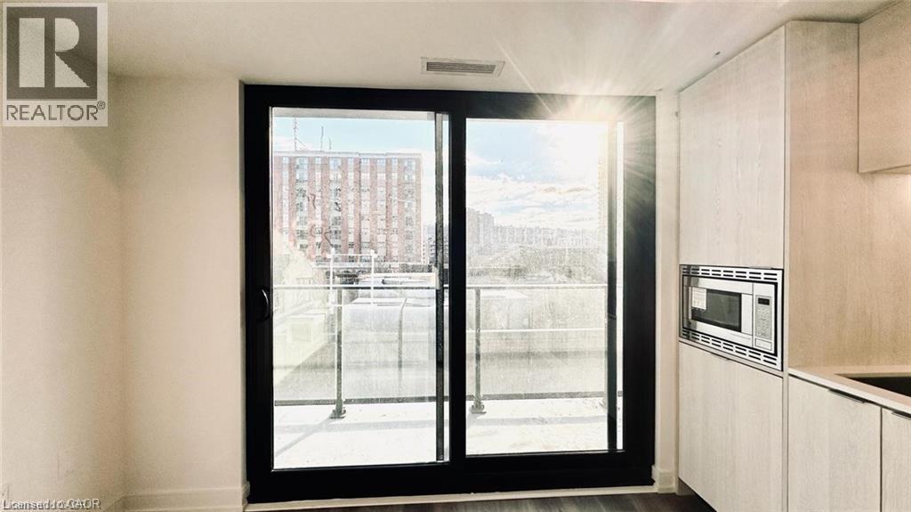 Kitchen with stainless steel microwave, light brown cabinetry, a city view, and dark wood finished floors - 1 Jarvis Street Unit# 509, Hamilton, ON - Indoor