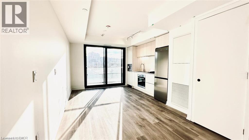 Kitchen featuring modern cabinets, stainless steel appliances, track lighting, light wood-type flooring, and white cabinets - 1 Jarvis Street Unit# 509, Hamilton, ON - Indoor Photo Showing Other Room
