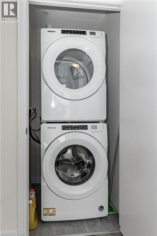 Laundry area featuring stacked washing machine and dryer - 60 Charles Street Unit# 2003, Kitchener, ON - Indoor Photo Showing Laundry Room