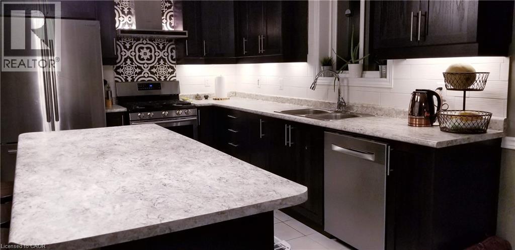 Kitchen with appliances with stainless steel finishes, light countertops, custom exhaust hood, light tile patterned floors, and backsplash - 118 Steeplechase Way, Waterloo, ON - Indoor Photo Showing Kitchen With Double Sink With Upgraded Kitchen