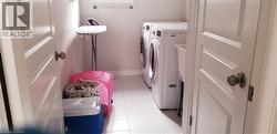 Laundry area with light tile patterned floors and separate washer and dryer -