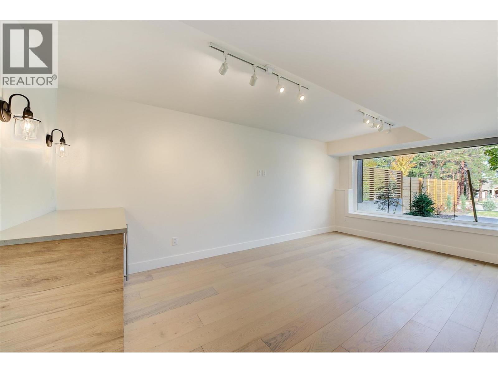 a spacious rec room with a quartz-topped bar, beverage fridge, and accent lighting. - 761 Barnaby Road, Kelowna, BC - Indoor Photo Showing Other Room