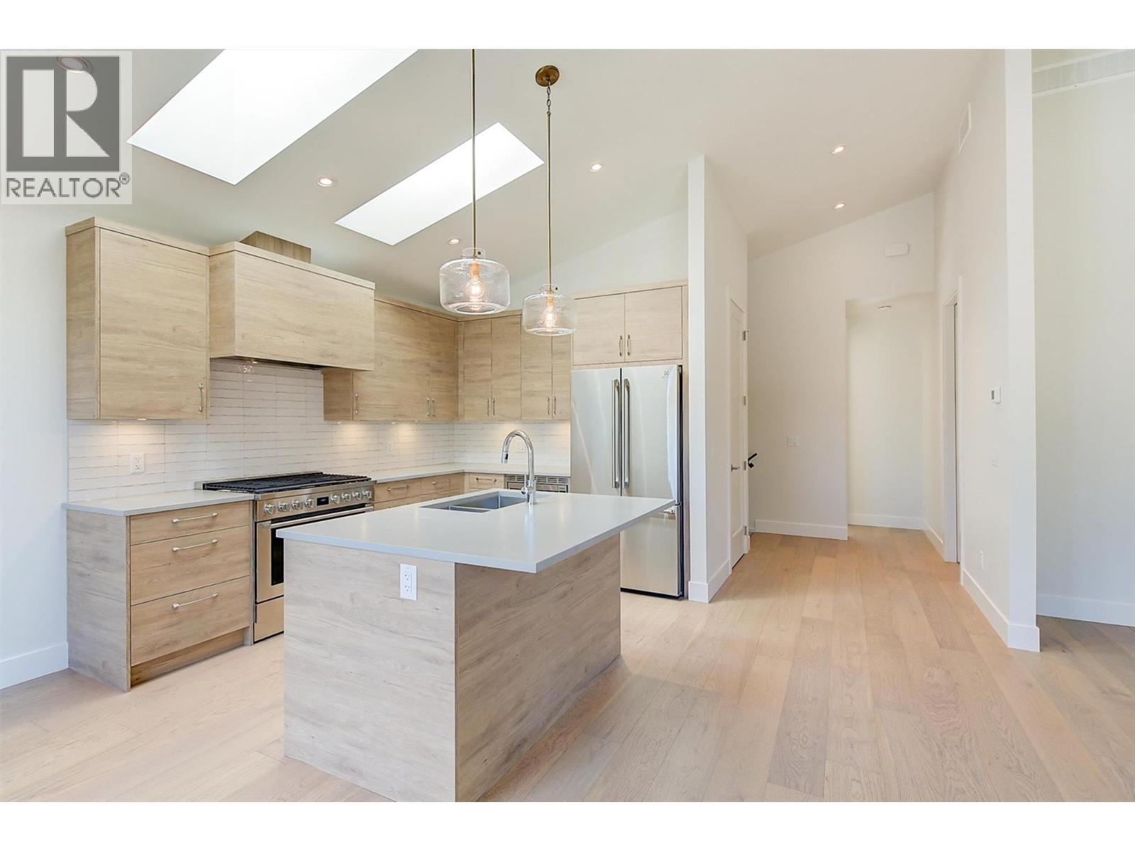 Soaring vaulted ceilings, skylights, and natural light fill the open-concept main floor - 761 Barnaby Road, Kelowna, BC - Indoor Photo Showing Kitchen With Upgraded Kitchen