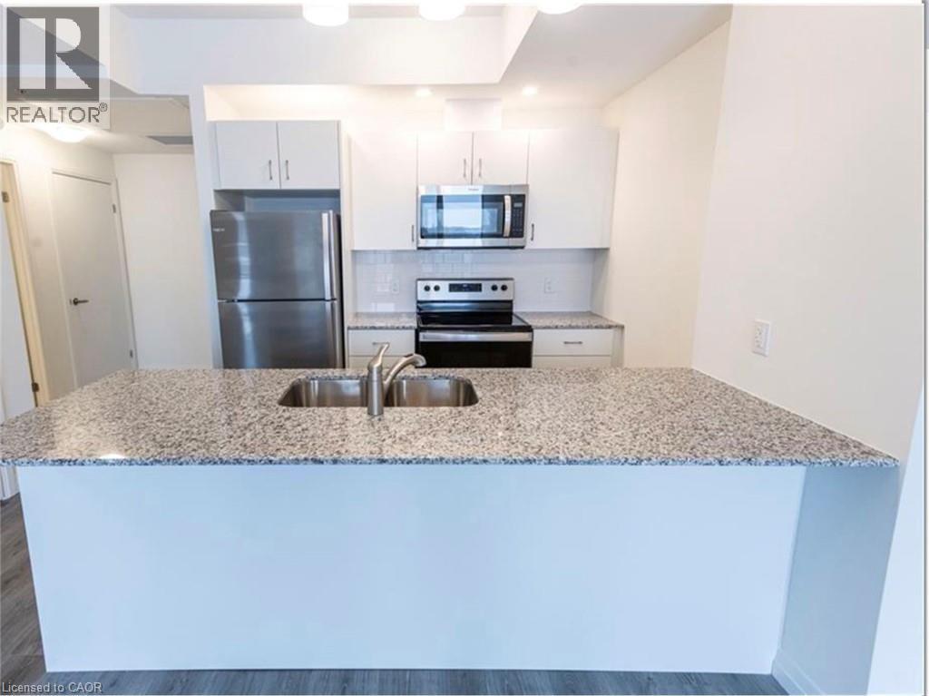 Kitchen featuring stainless steel appliances, backsplash, a peninsula, light stone countertops, and white cabinetry - 108 Garment Street Unit# 606, Kitchener, ON - Indoor Photo Showing Kitchen With Stainless Steel Kitchen With Double Sink With Upgraded Kitchen